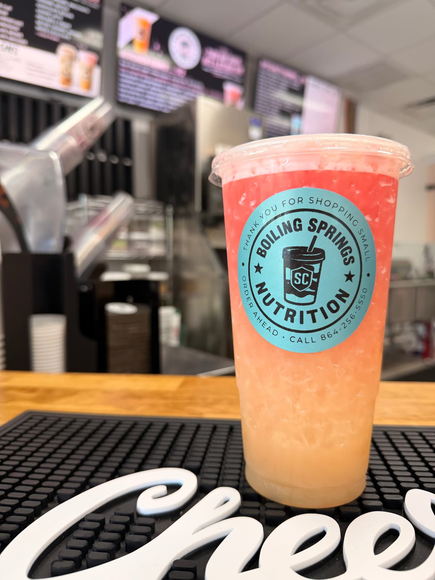 Original pink and peach layered BSN drink photographed at the café counter, with its authentic turquoise cup sticker
