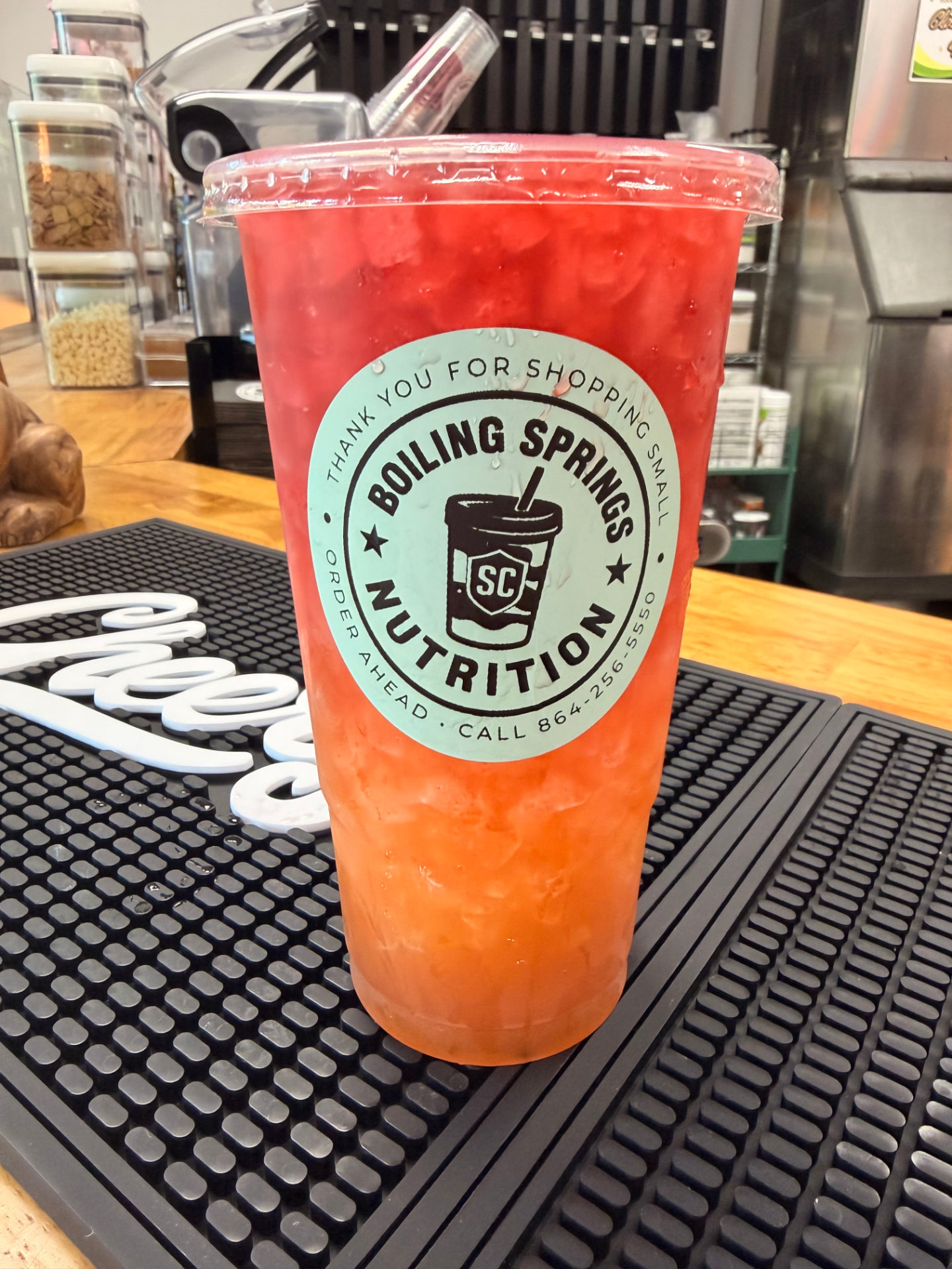 Original red and orange BSN drink photographed inside the café, with its authentic mint cup sticker